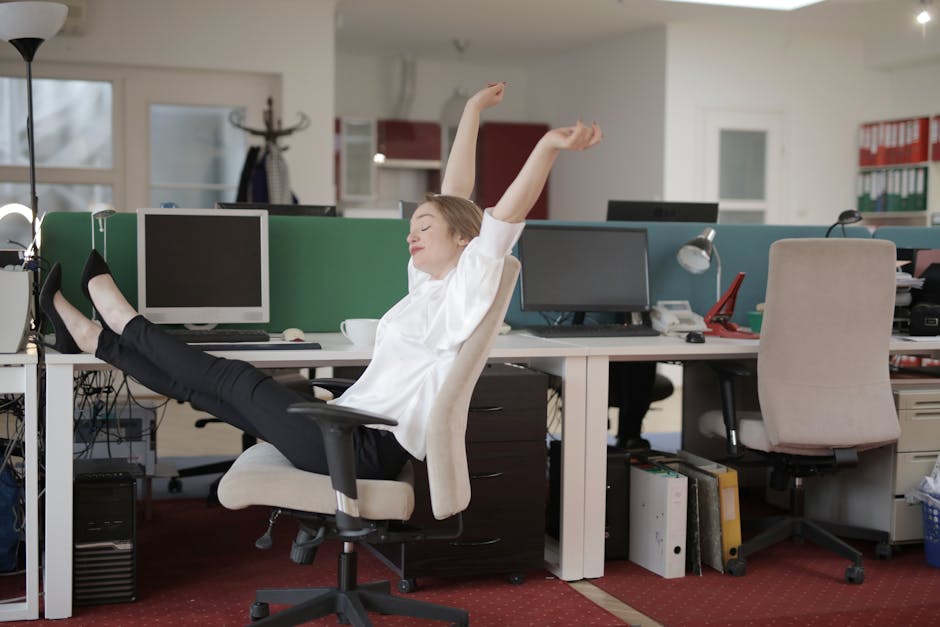 Office worker doing a gentle stretch at their desk with a smile